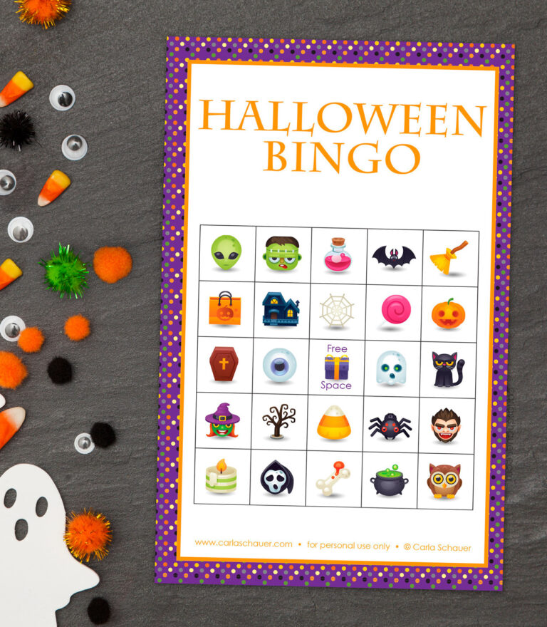 Colorful Halloween bingo card with grid of cute halloween icons. On slate background with candy corn, craft pom-poms, and googly eyes scattered on the side.